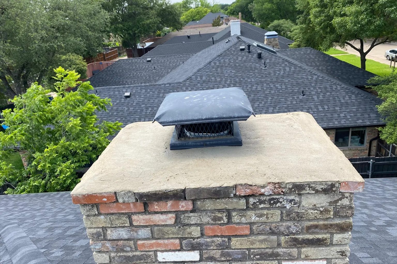 Stainless steel chimney cap on a repaired crown of a brick chimney, installed by Ember