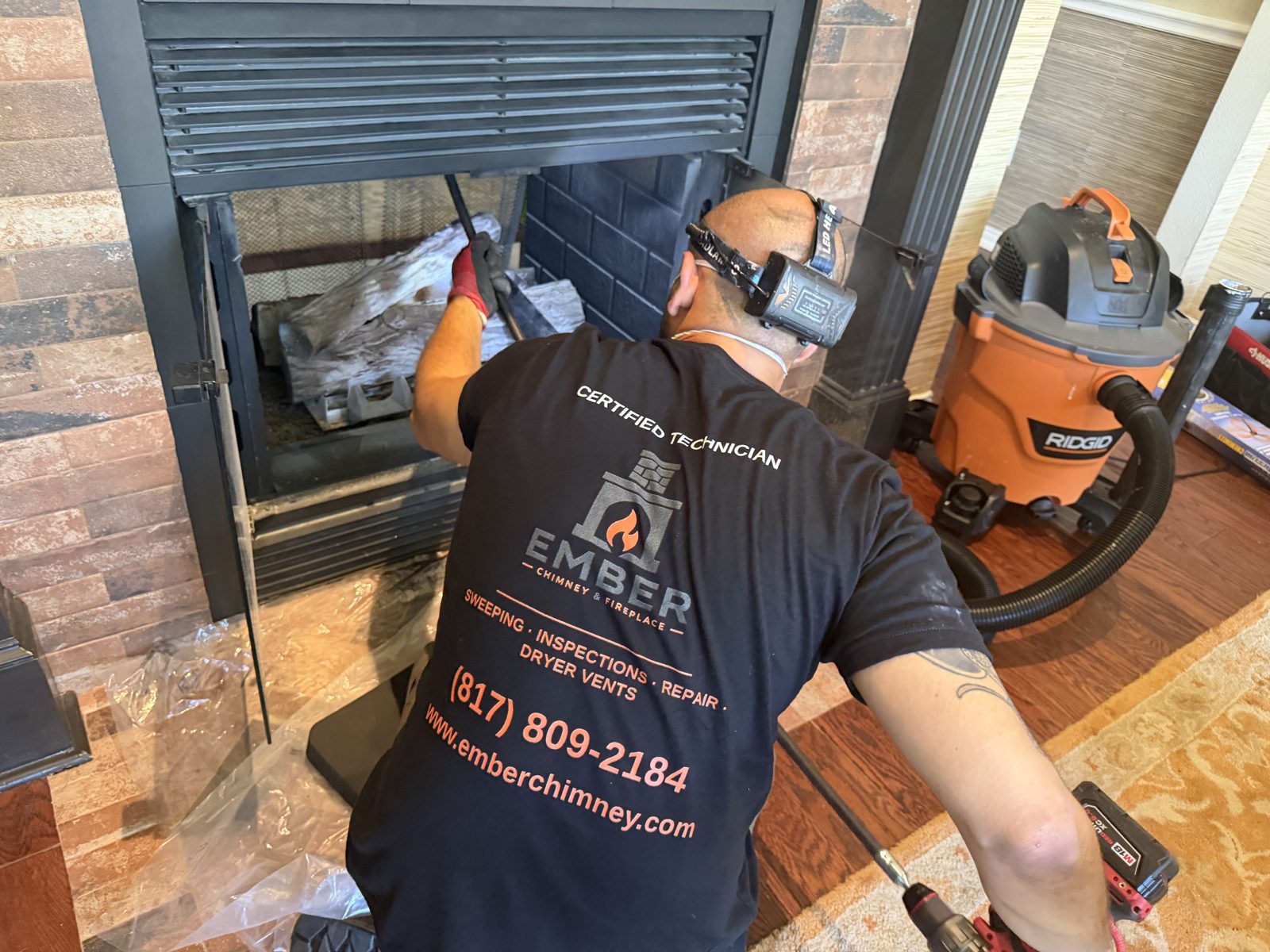 Ember Chimney & Fireplace technician cleaning a gas fireplace firebox with a HEPA vacuum before winter in Dallas-Fort Worth