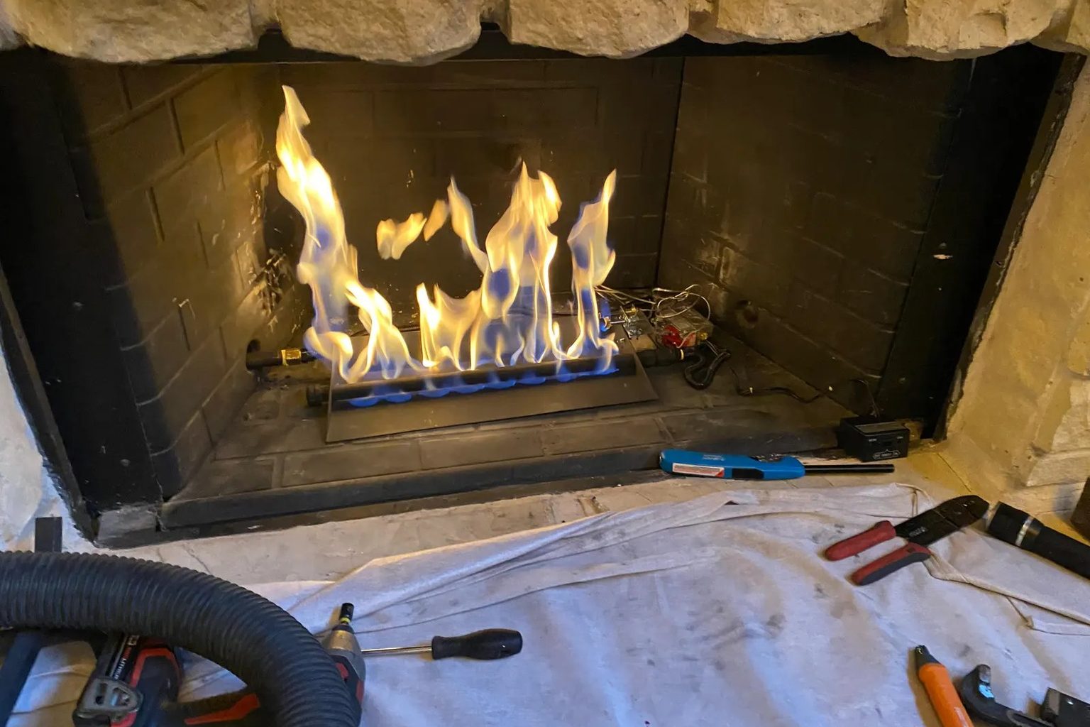 Ember technician testing the burner of a gas fireplace during an annual service